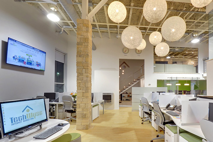 a newly renovated office in toronto. Two screens are mounted to the wall on the left. There is a row of desks on the right.