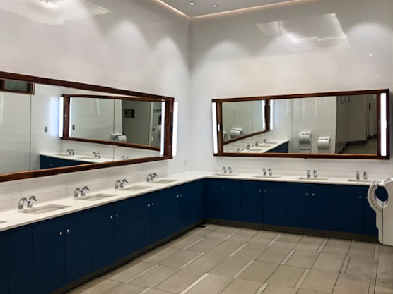 A washroom with two mirrors, a large wrap around counter top and black cabinets
